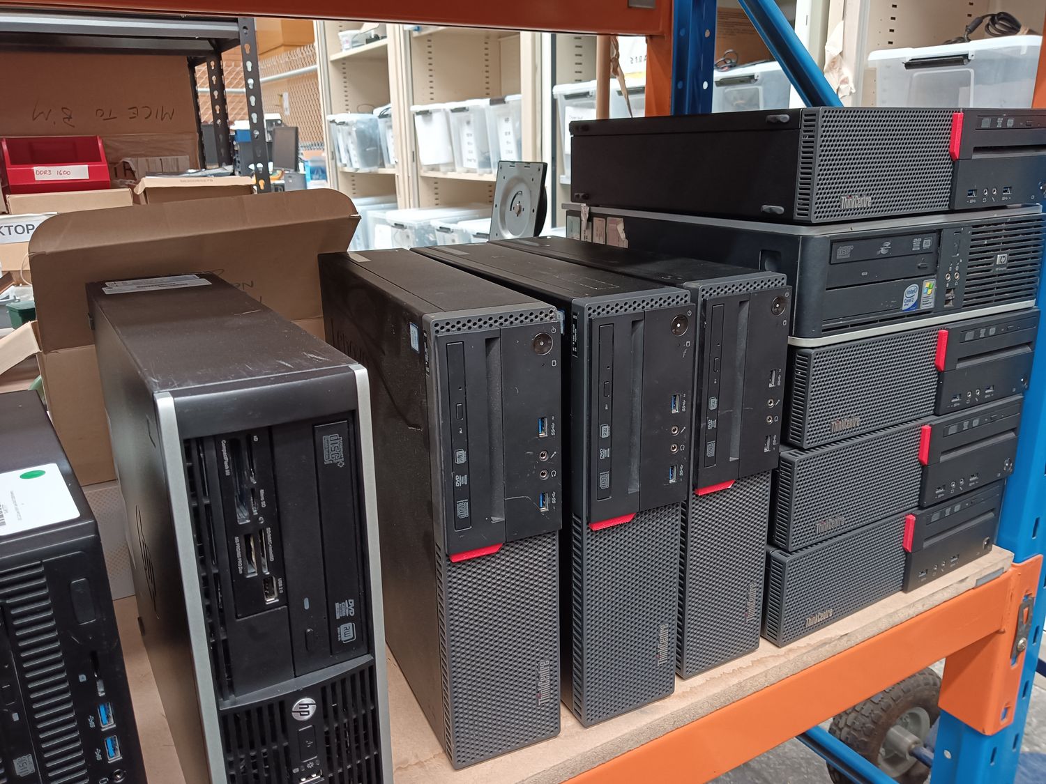 Refurbished Lenovo and HP desktop computers on a warehouse shelf